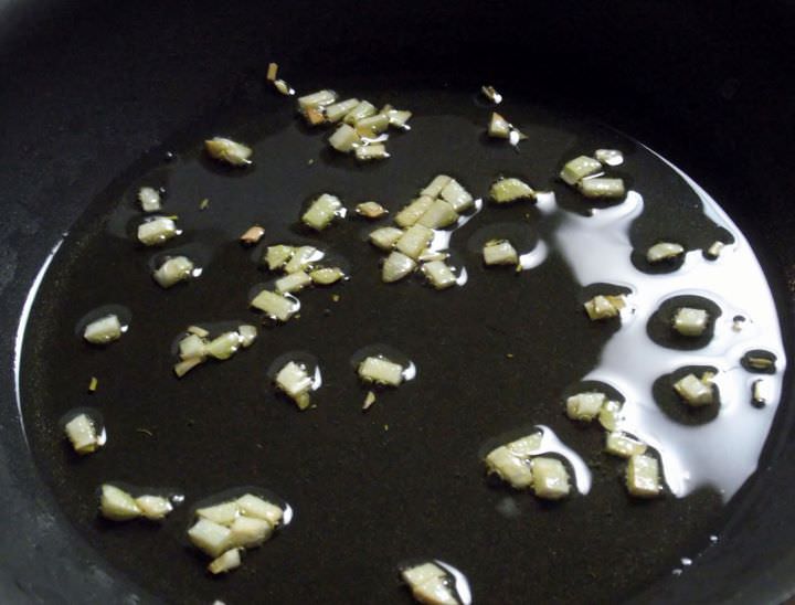 A non-stick skillet with garlic frying in olive oil.