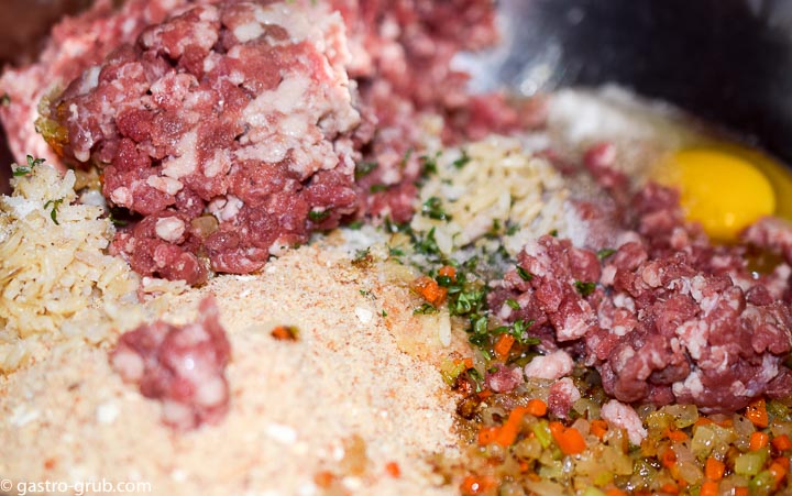 The ground beef, celery, carrot and onion mixture, breadcrumbs, rice, thyme, and eggs in a mixing bowl.