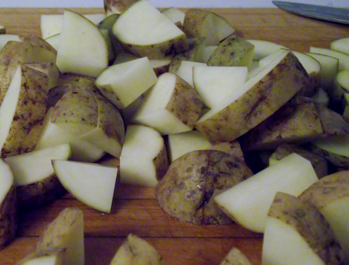 Potatoes on a cutting board quartered and sliced.