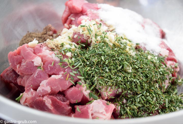 Pork, beef, pork fat, herbs, spices, and seasonings in a bowl.